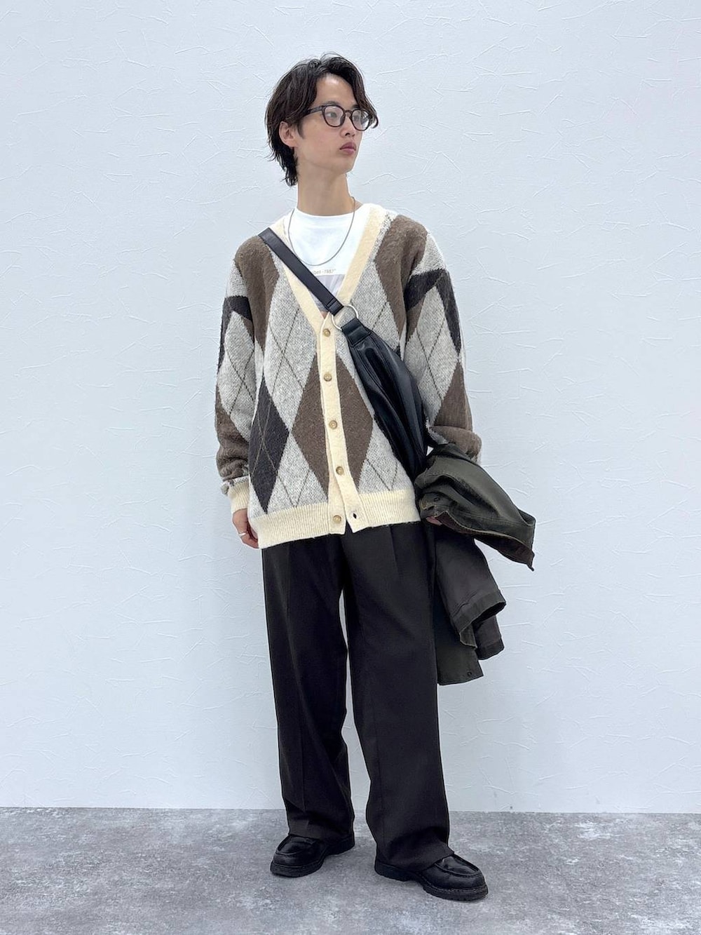 ホワイト系のカーディガン/ボレロ、ブラウン系のスラックス、グリーン系のブルゾンを着用したメンズの秋コーディネートの6枚目の写真