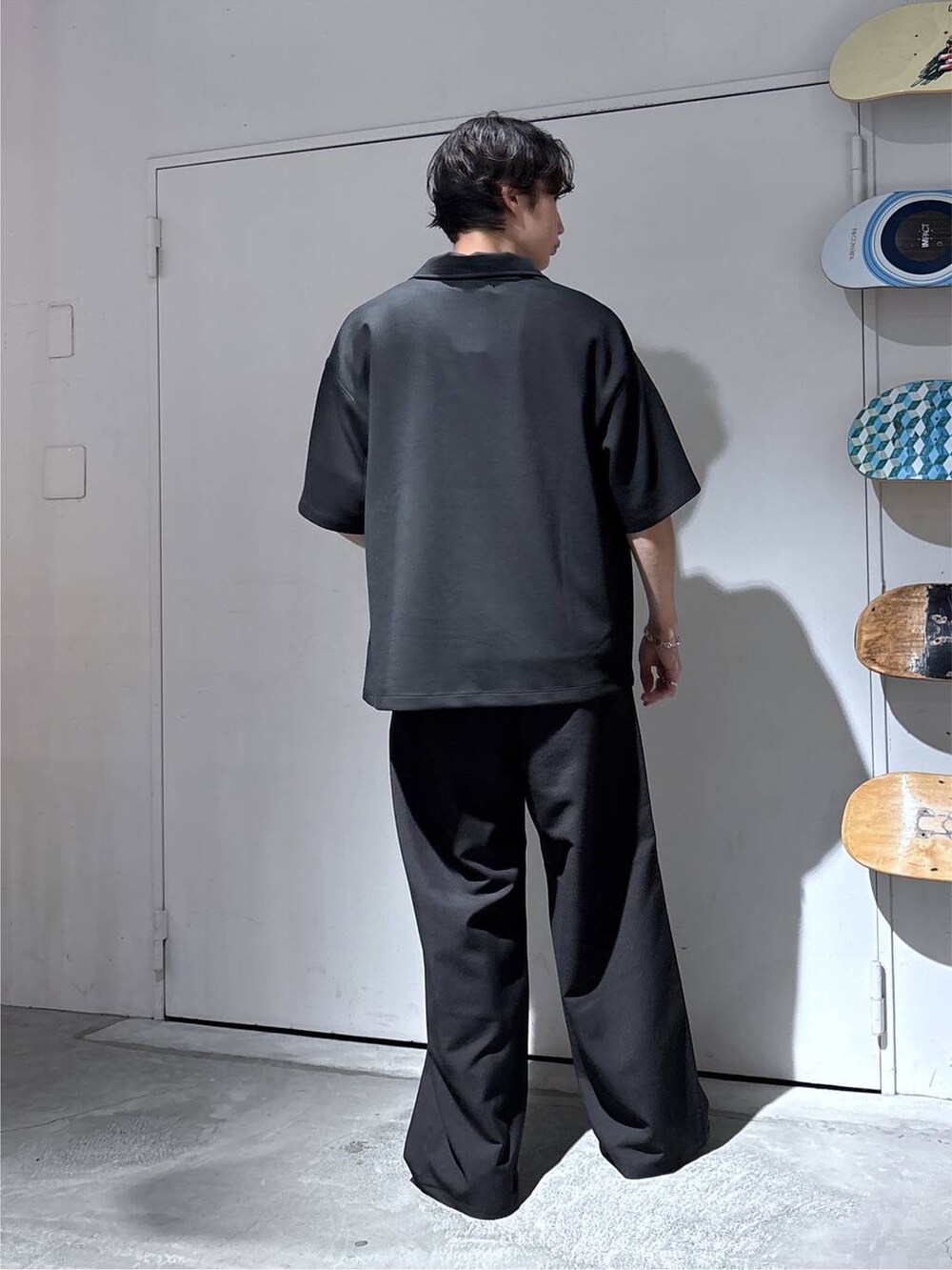 ブラック系のTシャツ/カットソー、ブラック系のローファー、ブラック系のスラックスを着用したメンズの夏コーディネートの5枚目の写真