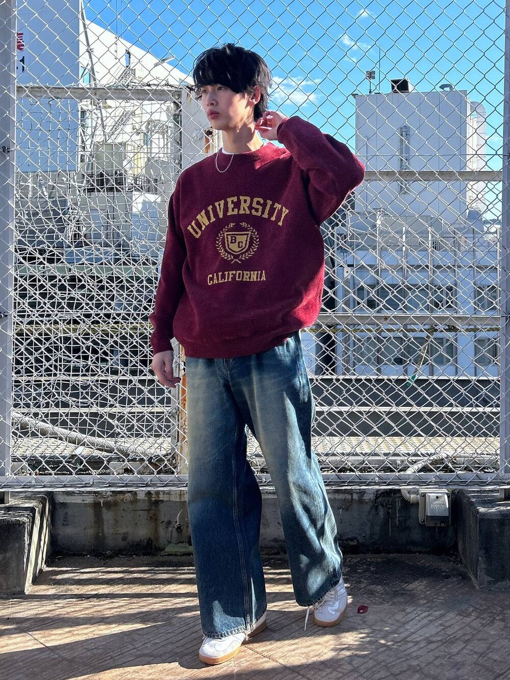 レッド系のニット/セーター、ホワイト系のTシャツ/カットソー、ブルー系のデニムパンツを着用したメンズの冬コーディネートの2枚目の写真