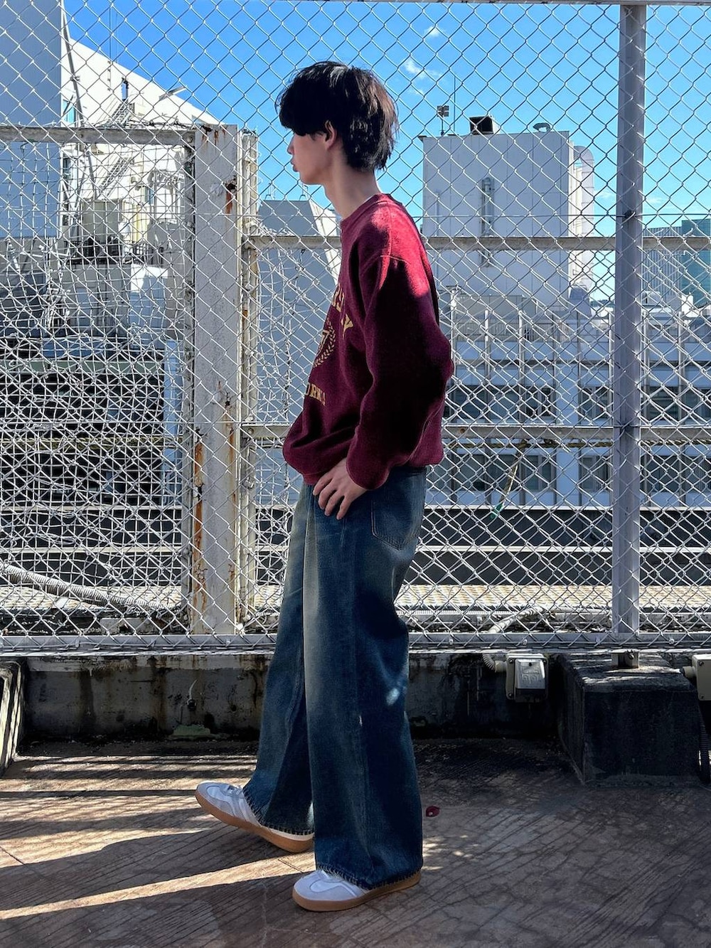 レッド系のニット/セーター、ホワイト系のTシャツ/カットソー、ブルー系のデニムパンツを着用したメンズの冬コーディネートの4枚目の写真