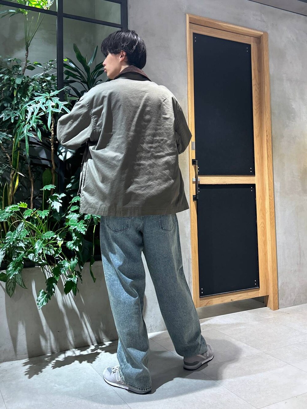 グレー系のスニーカー、ブルー系のデニムパンツ、グリーン系のブルゾンを着用したメンズの秋コーディネートの7枚目の写真