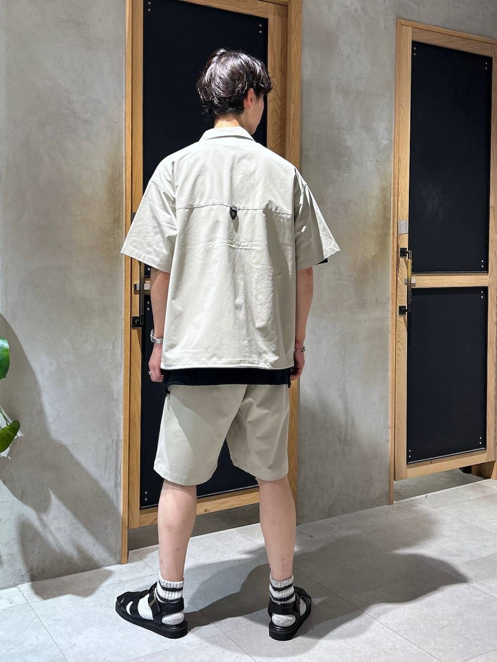 ブラック系のサンダル、ブラック系のTシャツ/カットソー、グレー系のチノパンツを着用したメンズの夏コーディネートの4枚目の写真