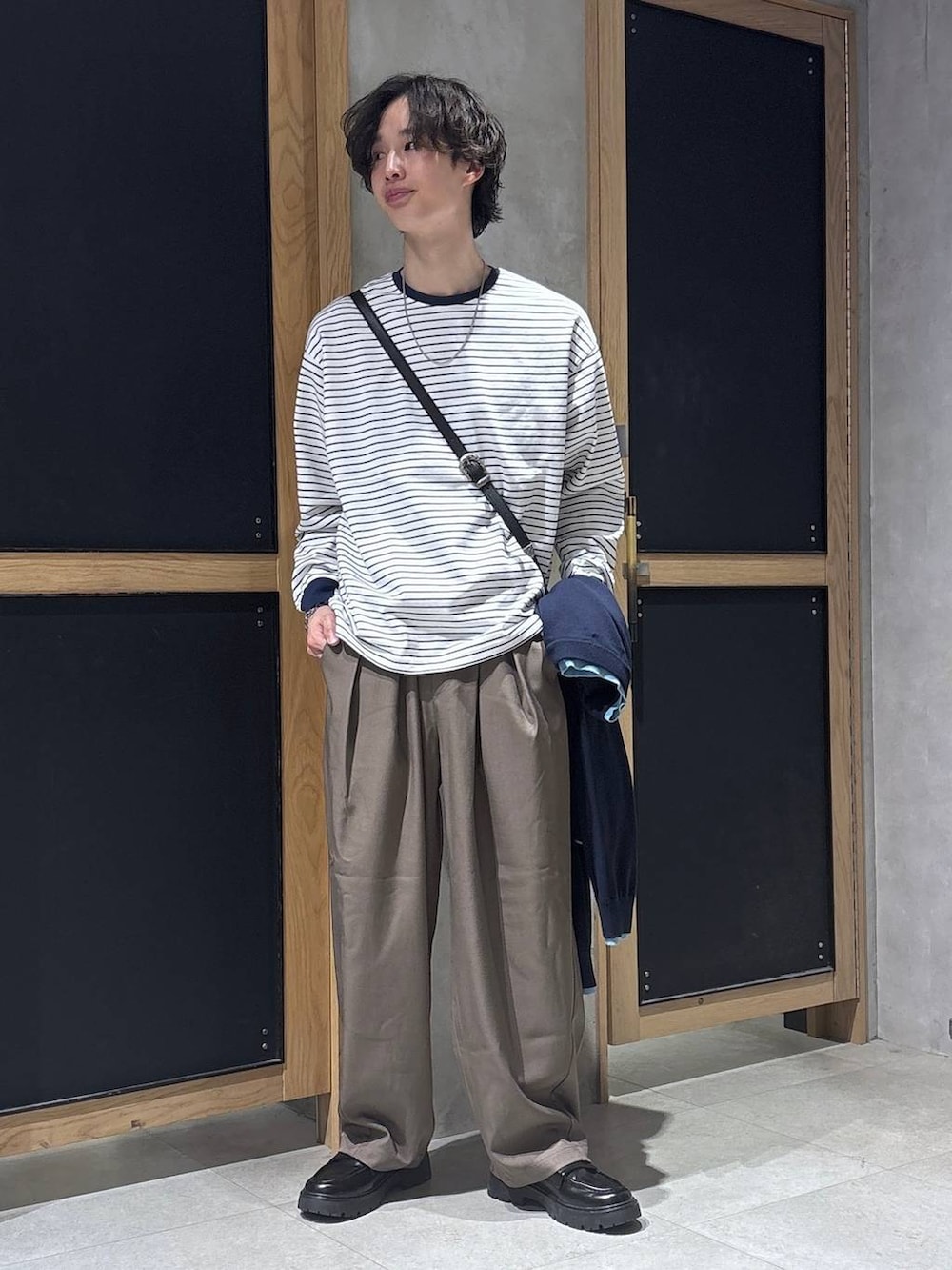 ブラック系のショルダーバッグ、ブラック系のドレスシューズ、ホワイト系のTシャツ/カットソーを着用したメンズの春コーディネートの6枚目の写真