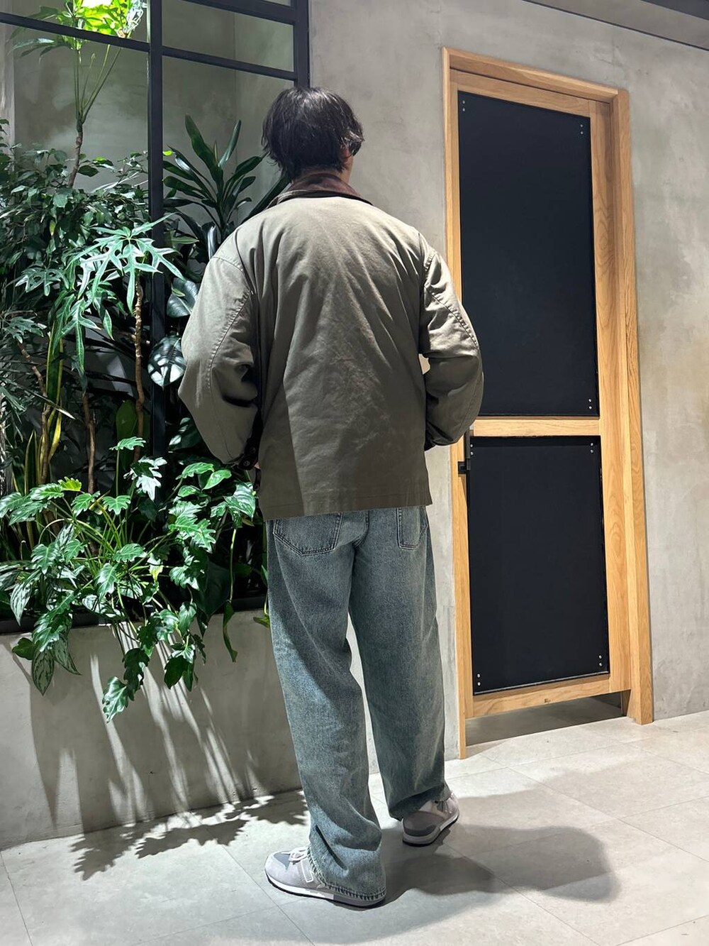 グレー系のスニーカー、ブルー系のデニムパンツ、グリーン系のブルゾンを着用したメンズの秋コーディネートの5枚目の写真
