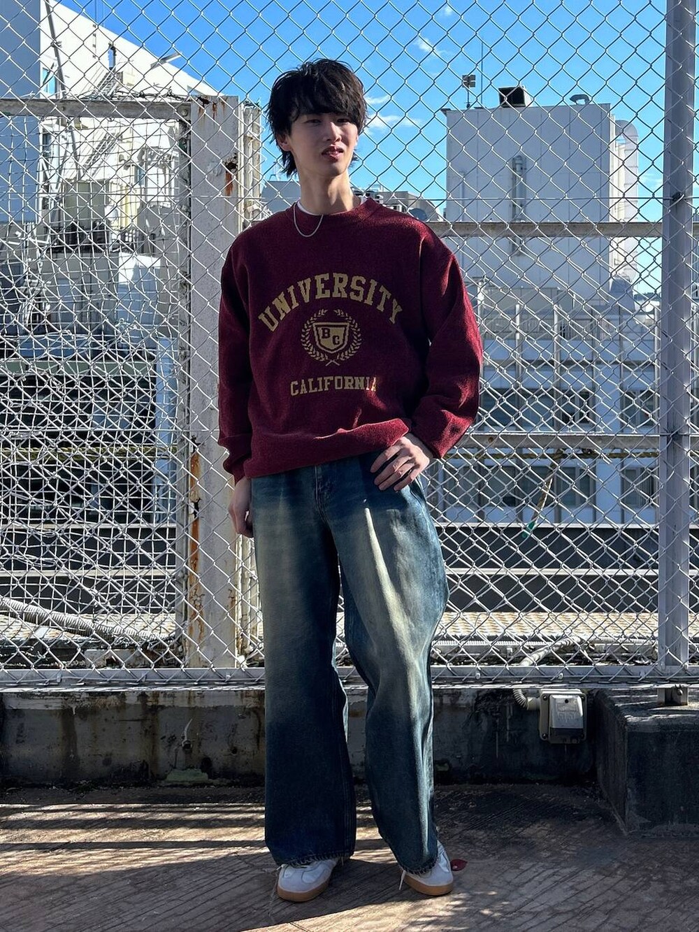 レッド系のニット/セーター、ホワイト系のTシャツ/カットソー、ブルー系のデニムパンツを着用したメンズの冬コーディネートの3枚目の写真