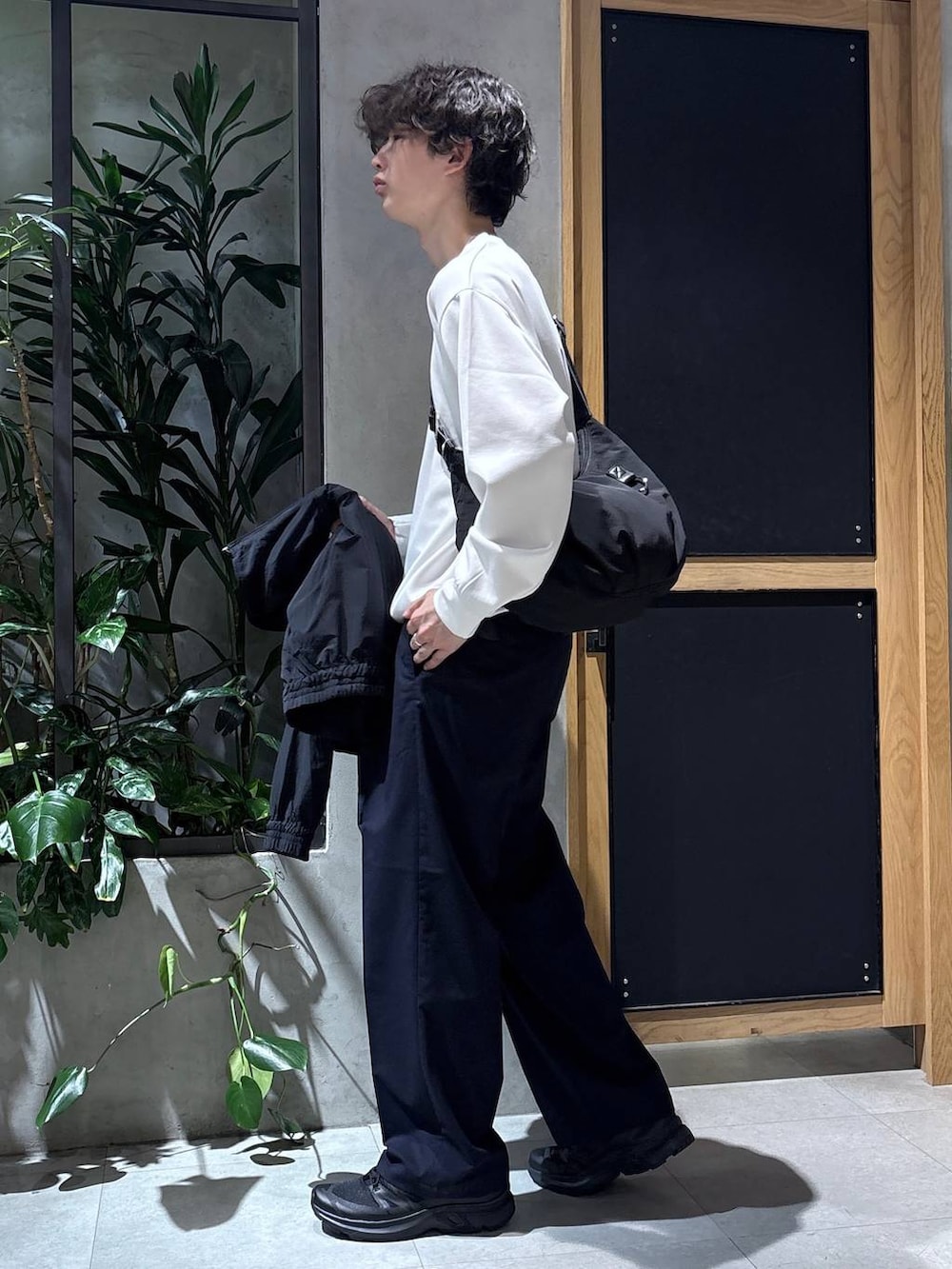 ブラック系のスニーカー、ブルー系のスラックス、ブラック系のショルダーバッグを着用したメンズの春コーディネートの4枚目の写真