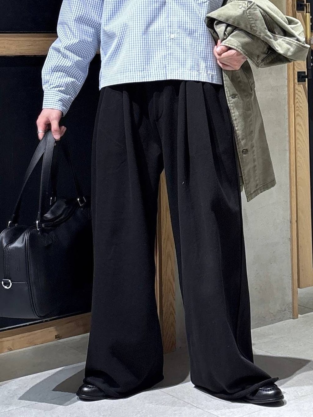 ブラック系のボストンバッグ、ブラック系のローファー、グリーン系のミリタリージャケットを着用したメンズの春コーディネートの3枚目の写真