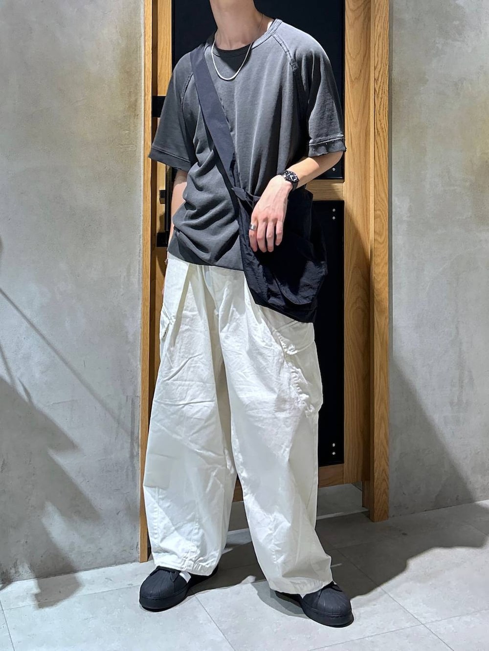 ホワイト系のカーゴパンツ、グレー系のTシャツ/カットソー、ブラック系のショルダーバッグを着用したメンズの秋コーディネートの2枚目の写真