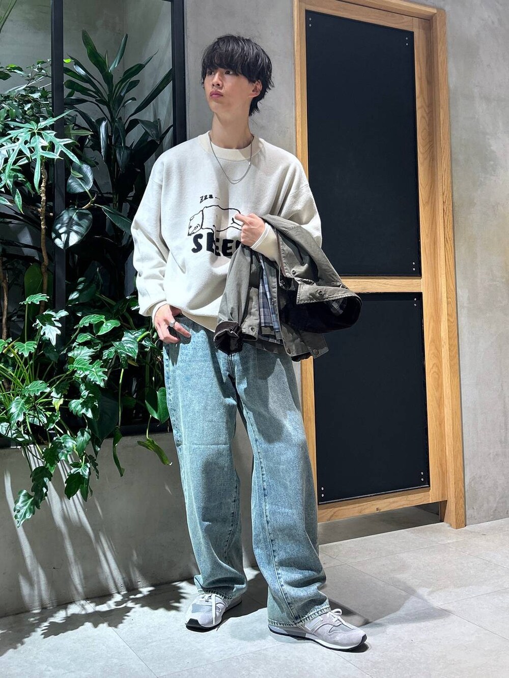 グレー系のスニーカー、ブルー系のデニムパンツ、グリーン系のブルゾンを着用したメンズの秋コーディネートの2枚目の写真