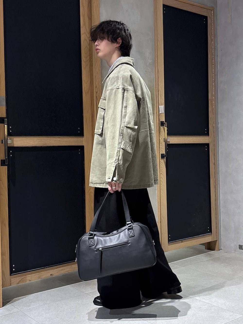 ブラック系のボストンバッグ、ブラック系のローファー、グリーン系のミリタリージャケットを着用したメンズの春コーディネートの8枚目の写真