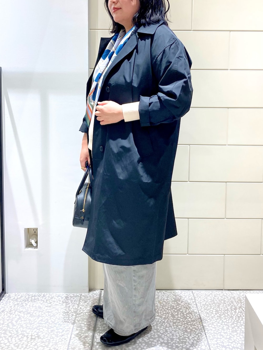 ブラック系のトレンチコート、ブラック系のショルダーバッグ、グレー系のデニムパンツを着用したレディースの秋コーディネートの3枚目の写真