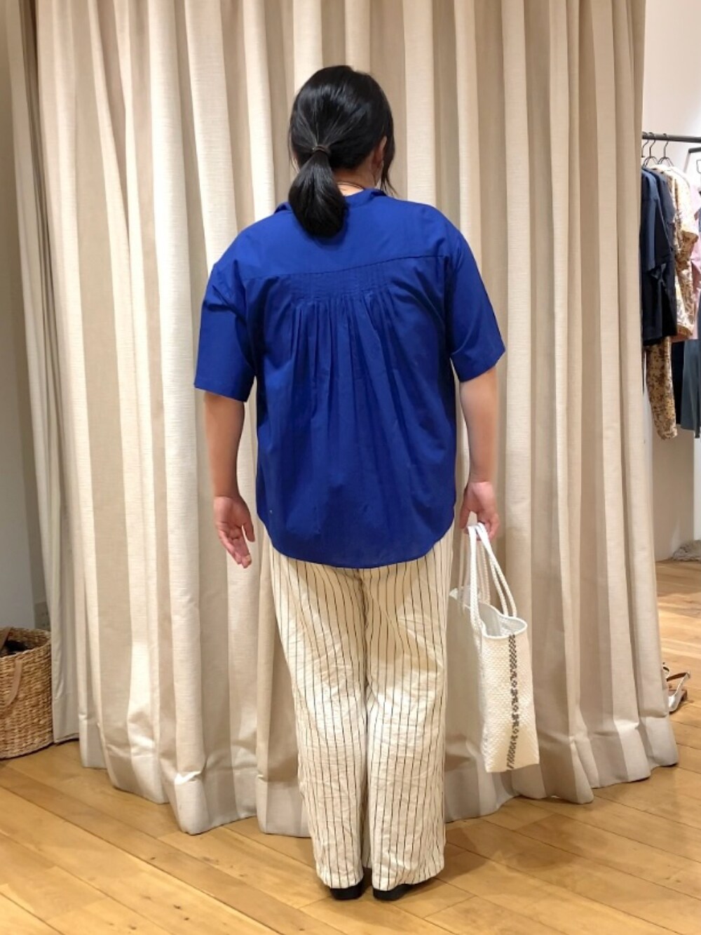 ブルー系のシャツ/ブラウス、ホワイト系のかごバッグ、その他のネックレスを着用したレディースの春コーディネートの4枚目の写真