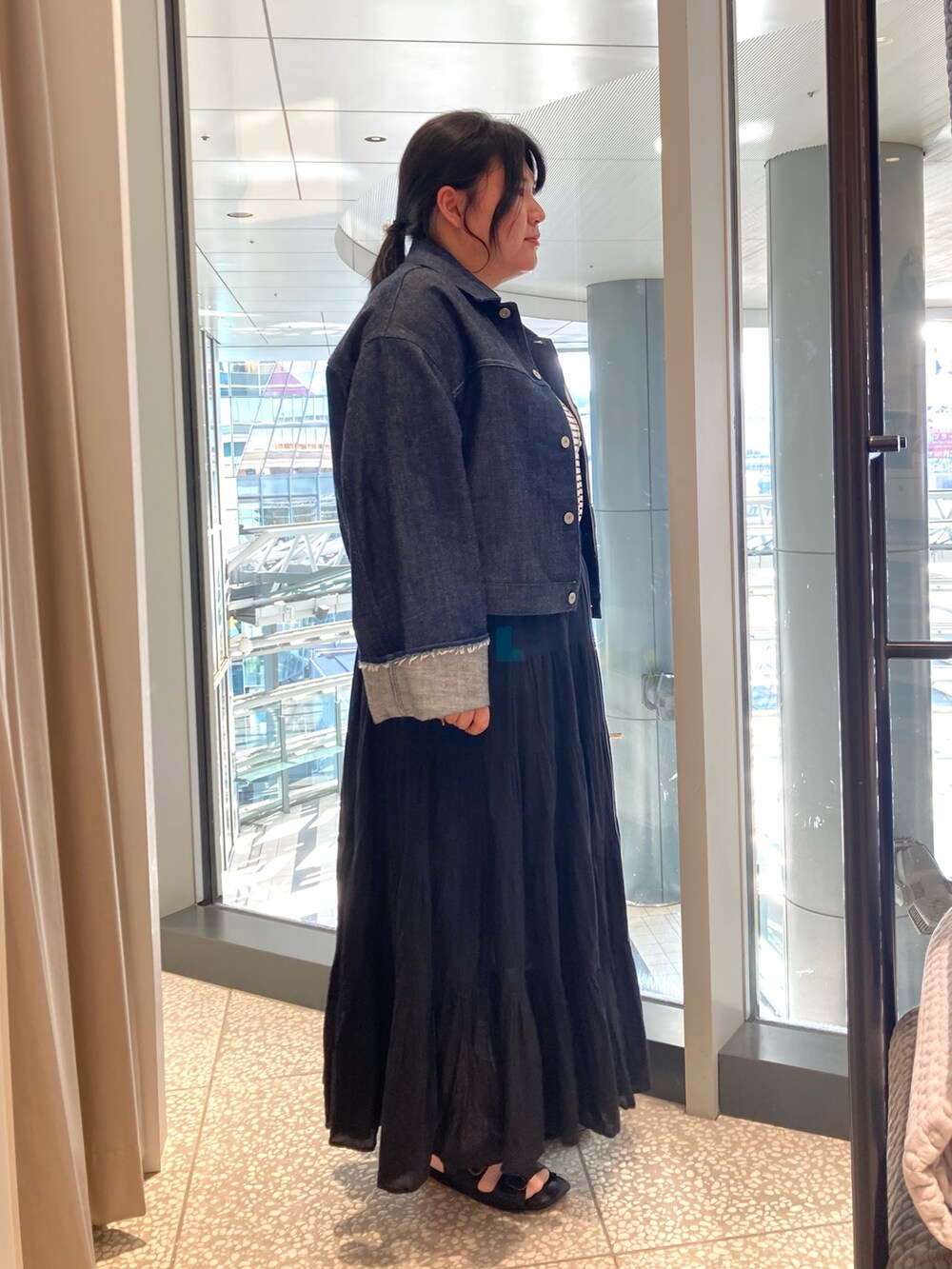 ブルー系のデニムジャケット、ベージュ系のトートバッグ、ブラック系のサンダルを着用したレディースの春コーディネートの4枚目の写真