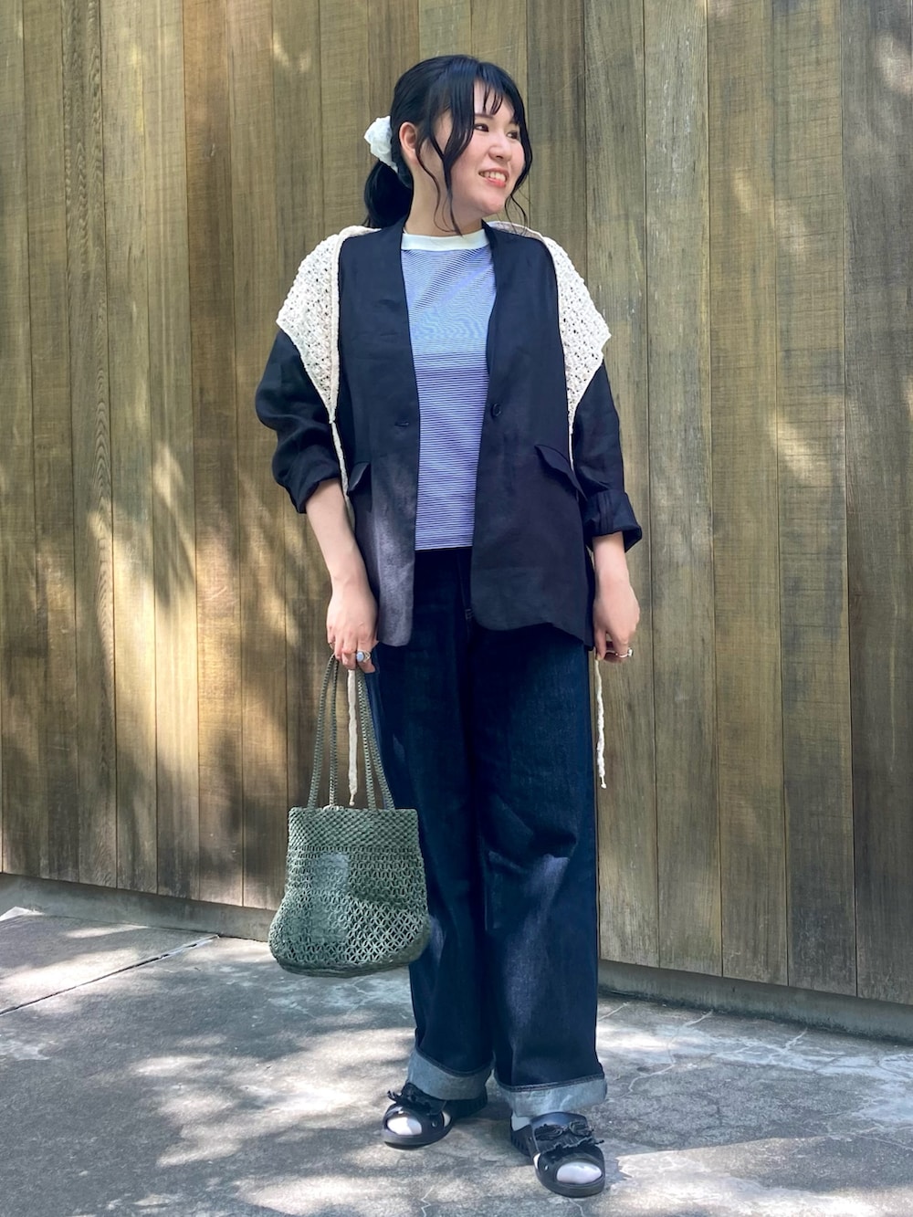 グリーン系のかごバッグ、ブルー系のデニムパンツ、ブルー系のTシャツ/カットソーを着用したレディースの春コーディネートの4枚目の写真