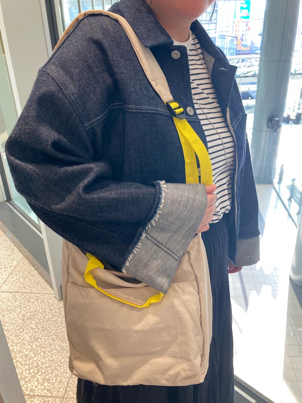 ブルー系のデニムジャケット、ベージュ系のトートバッグ、ブラック系のサンダルを着用したレディースの春コーディネートの6枚目の写真