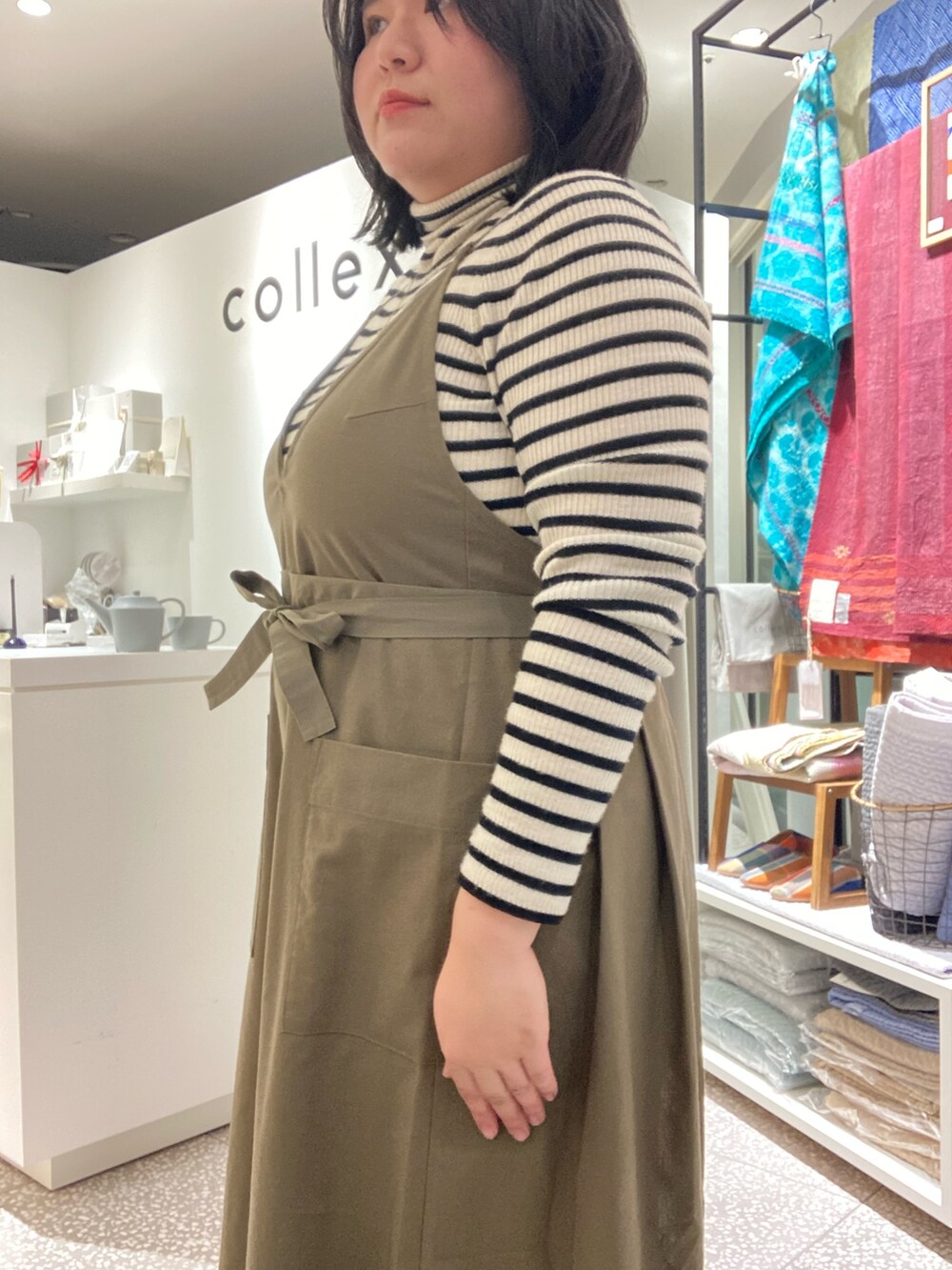 ブラウン系のその他パンツ、ブラック系のその他シューズ、グリーン系のエプロンを着用したレディースの冬コーディネートの6枚目の写真