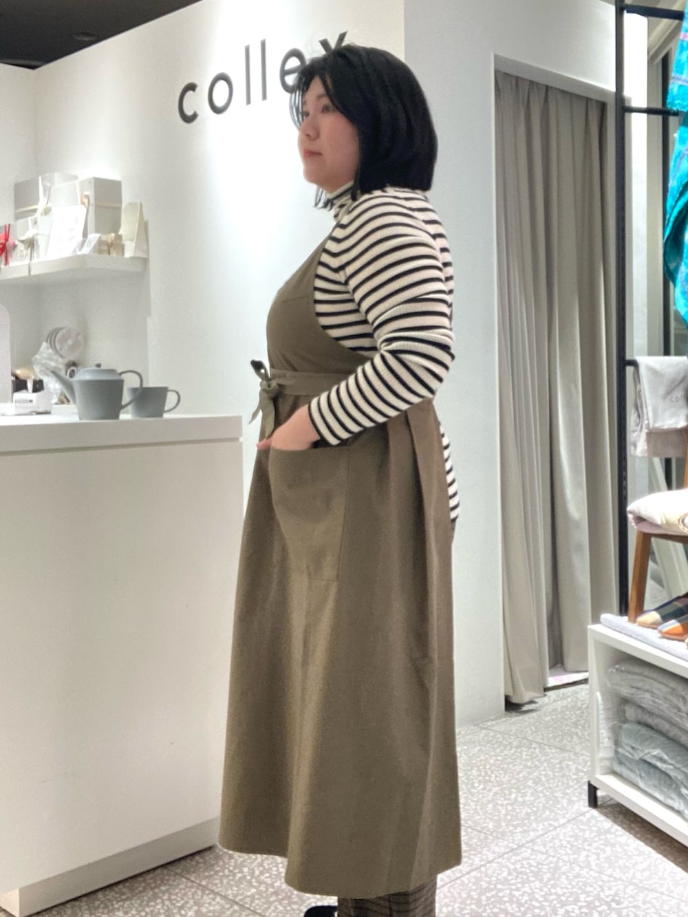 ブラウン系のその他パンツ、ブラック系のその他シューズ、グリーン系のエプロンを着用したレディースの冬コーディネートの3枚目の写真