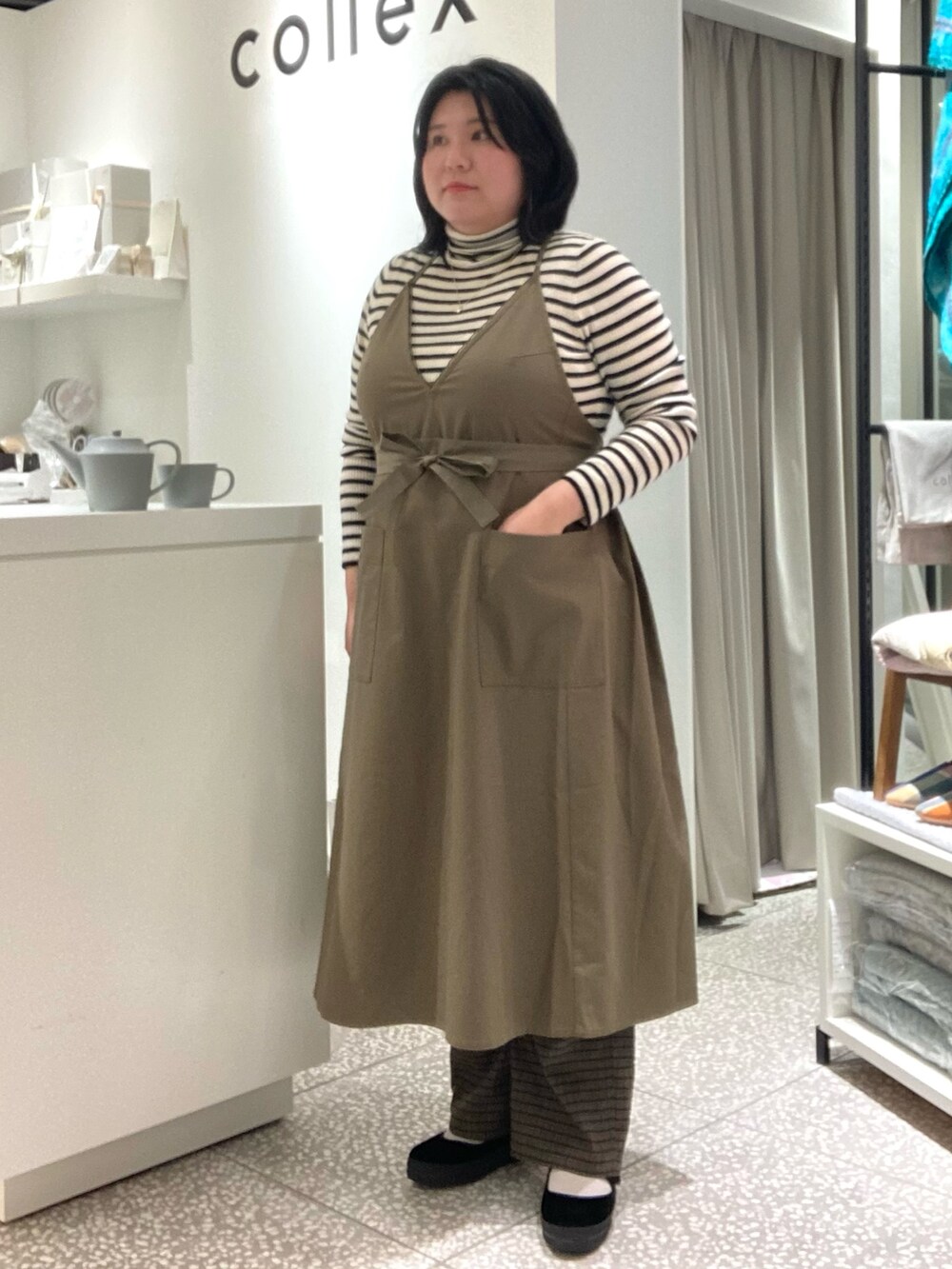 ブラウン系のその他パンツ、ブラック系のその他シューズ、グリーン系のエプロンを着用したレディースの冬コーディネートの2枚目の写真