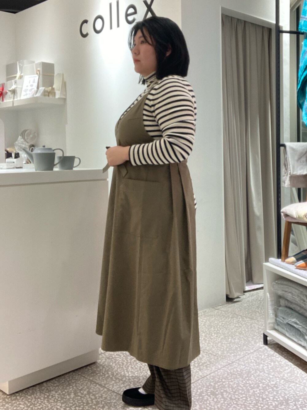 ブラウン系のその他パンツ、ブラック系のその他シューズ、グリーン系のエプロンを着用したレディースの冬コーディネートの5枚目の写真