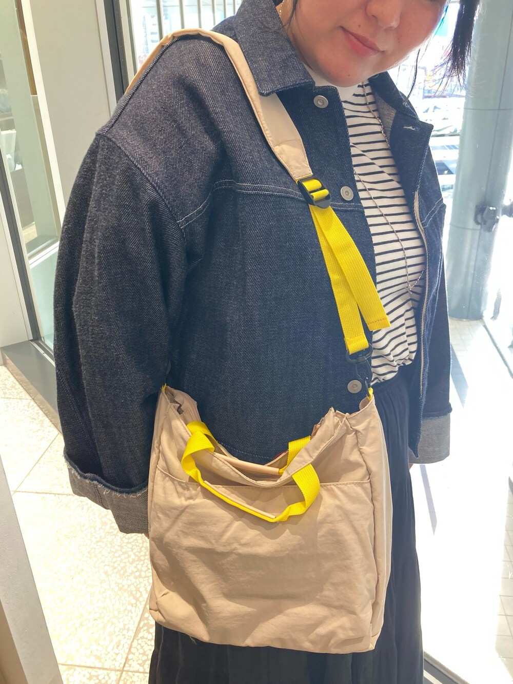 ブルー系のデニムジャケット、ベージュ系のトートバッグ、ブラック系のサンダルを着用したレディースの春コーディネートの7枚目の写真