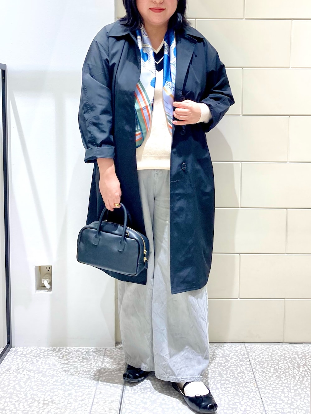 ブラック系のトレンチコート、ブラック系のショルダーバッグ、グレー系のデニムパンツを着用したレディースの秋コーディネートの4枚目の写真