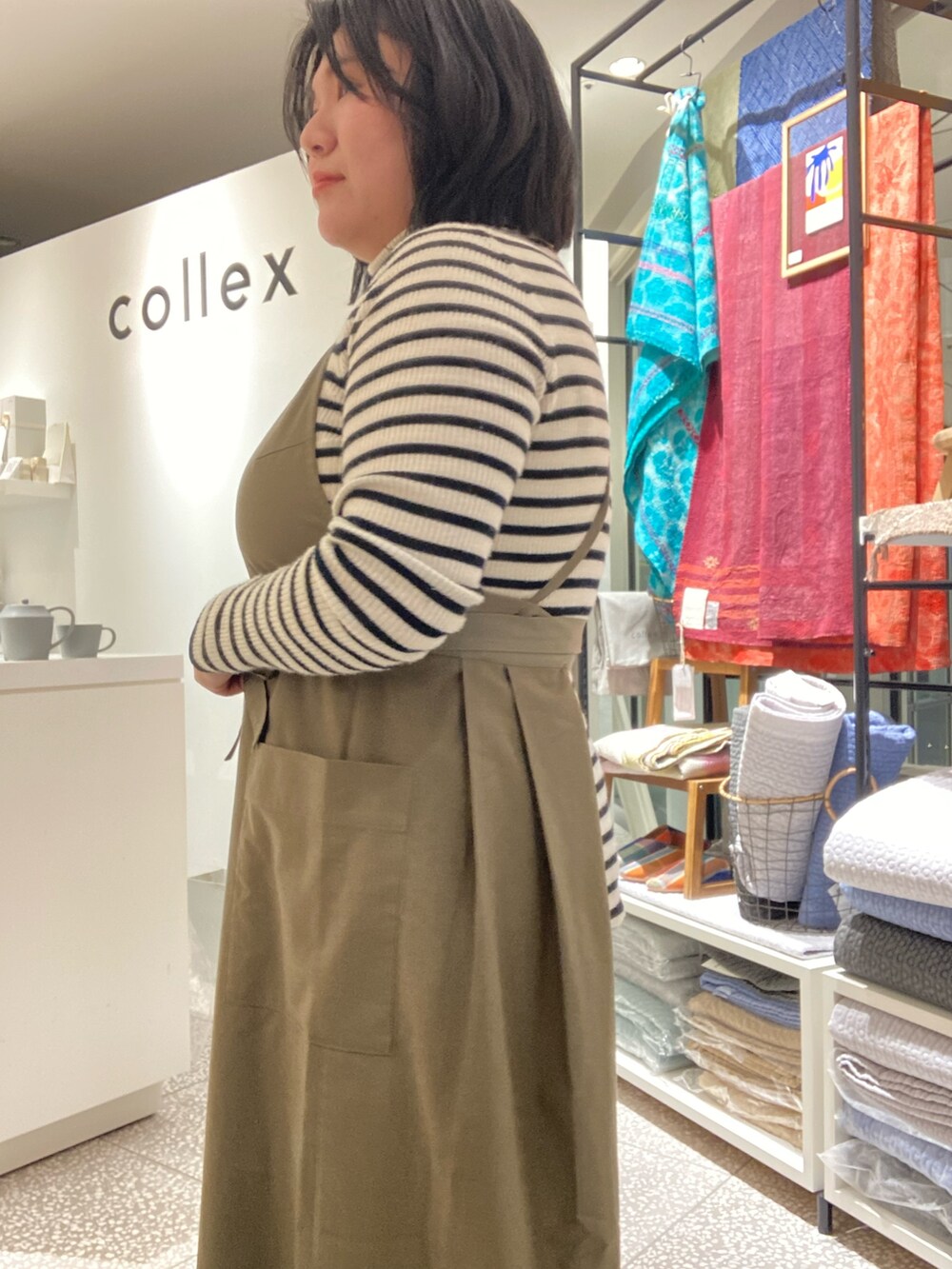 ブラウン系のその他パンツ、ブラック系のその他シューズ、グリーン系のエプロンを着用したレディースの冬コーディネートの7枚目の写真