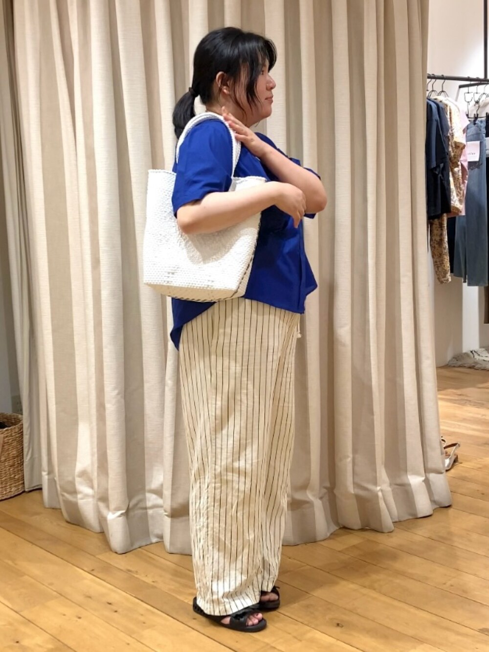 ブルー系のシャツ/ブラウス、ホワイト系のかごバッグ、その他のネックレスを着用したレディースの春コーディネートの6枚目の写真