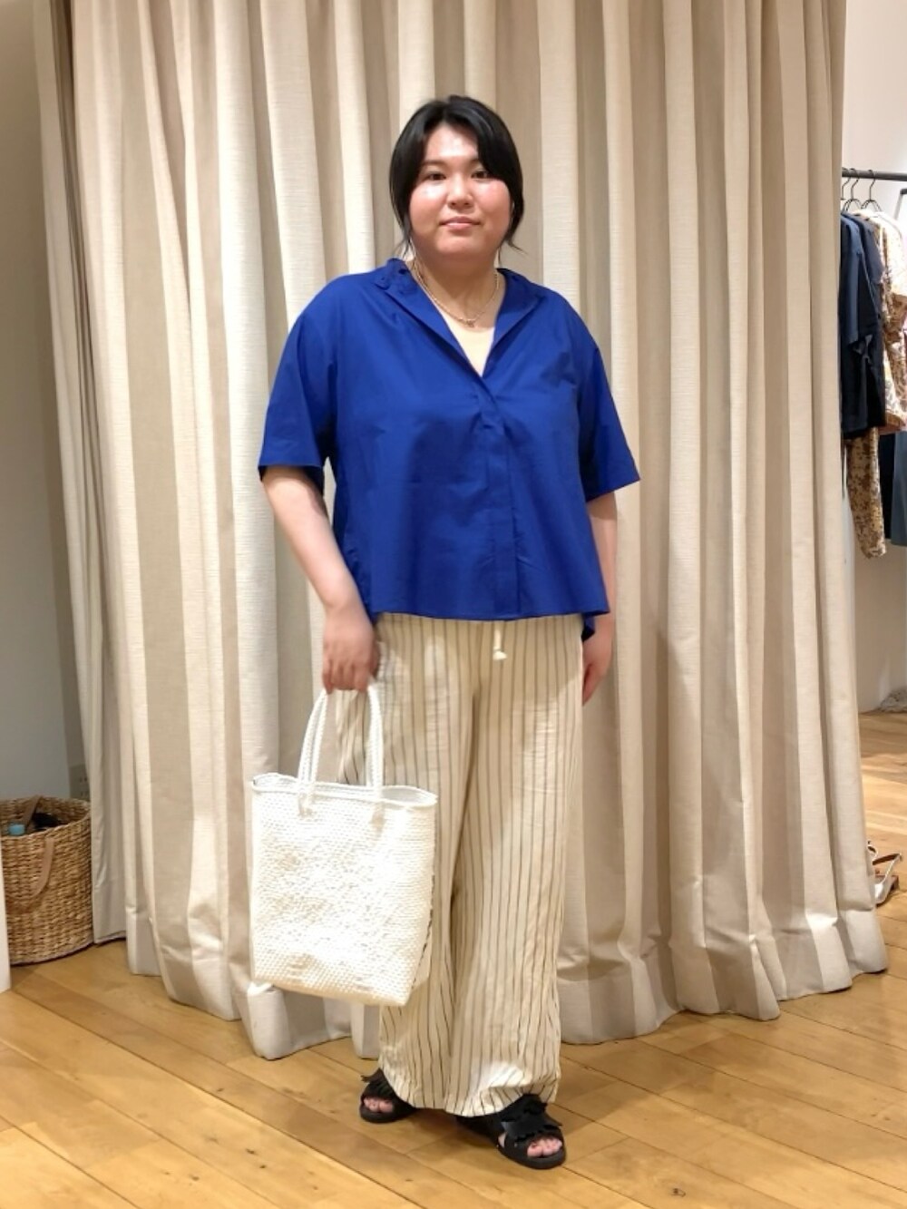 ブルー系のシャツ/ブラウス、ホワイト系のかごバッグ、その他のネックレスを着用したレディースの春コーディネートの2枚目の写真