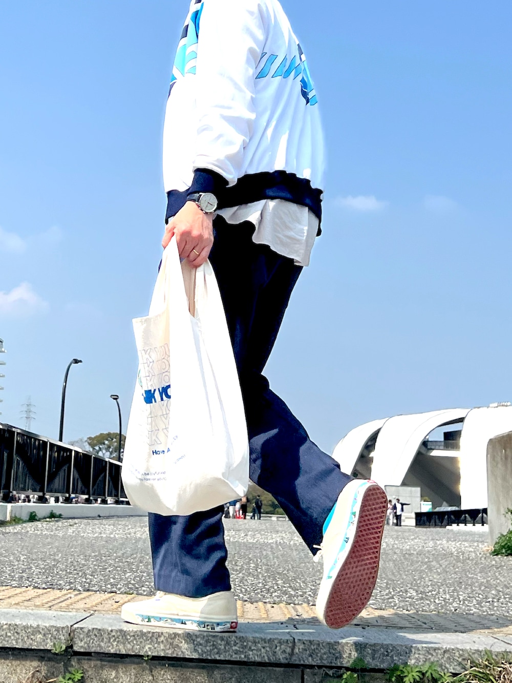 ホワイト系のジャージ、ブルー系のスラックス、ホワイト系のスニーカーを着用したメンズの春コーディネートの2枚目の写真