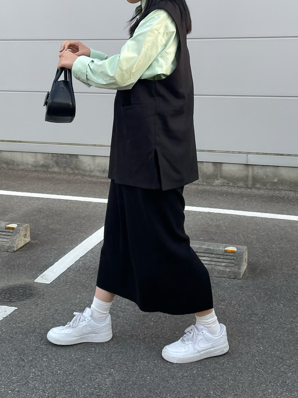 ブラック系のバッグ、ブラック系のベスト、ブラック系のスカートを着用したレディースの秋コーディネートの2枚目の写真