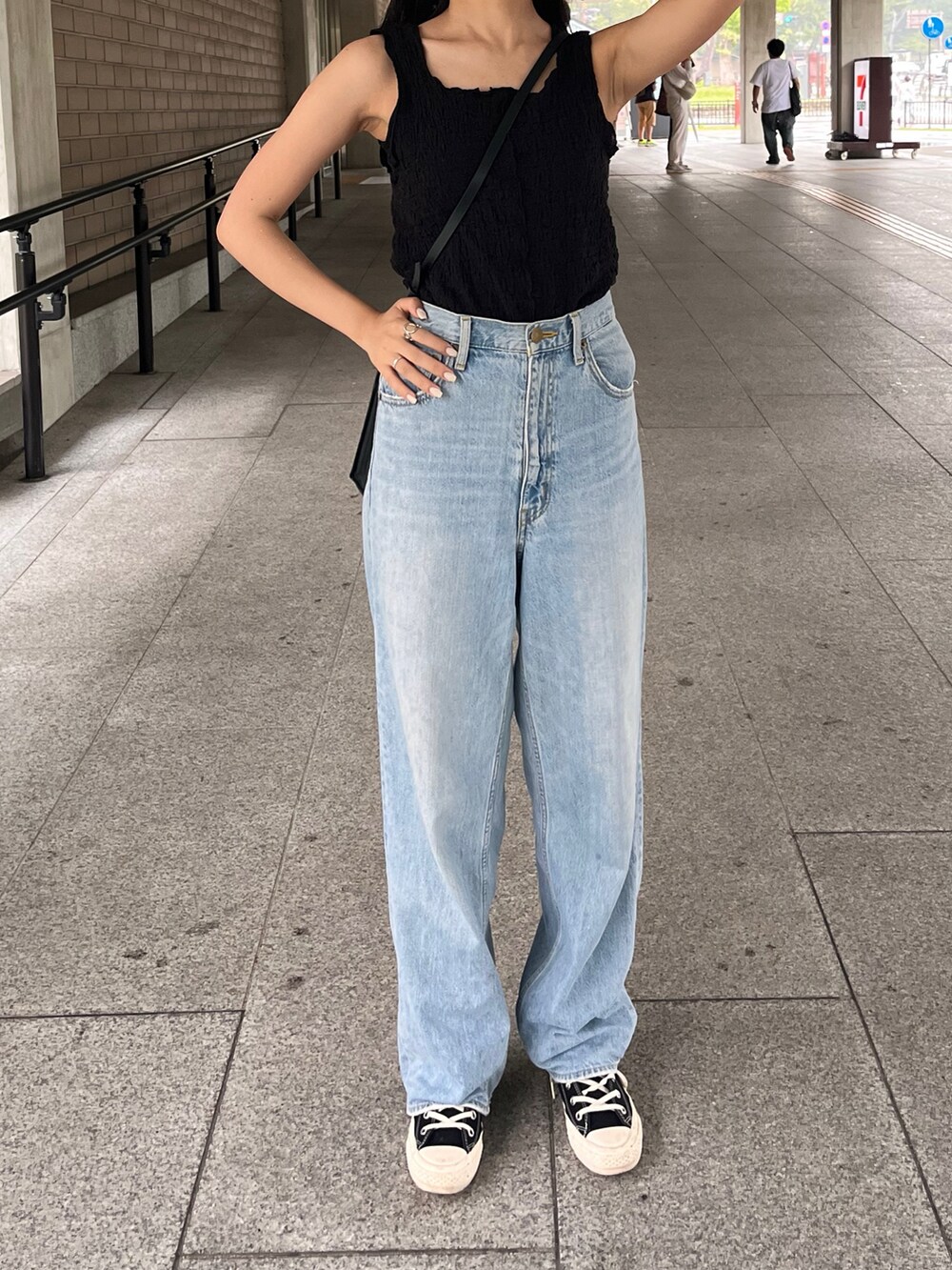ブルー系のデニムパンツ、ブラック系のスニーカーを着用したレディースの秋コーディネートの2枚目の写真