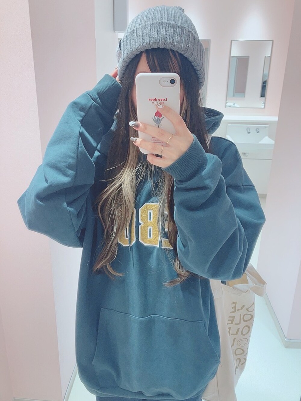 ブルー系のデニムパンツ、グリーン系のパーカー、ホワイト系のブーツを着用したレディースの冬コーディネートの2枚目の写真