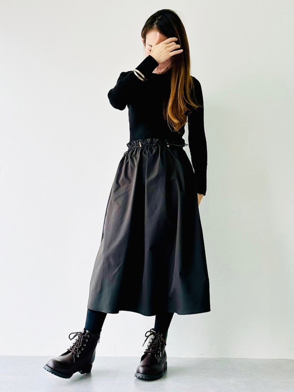 ブラウン系のチェスターコート、ブラック系のワンピース、ブラウン系のブーツを着用したレディースの冬コーディネートの2枚目の写真