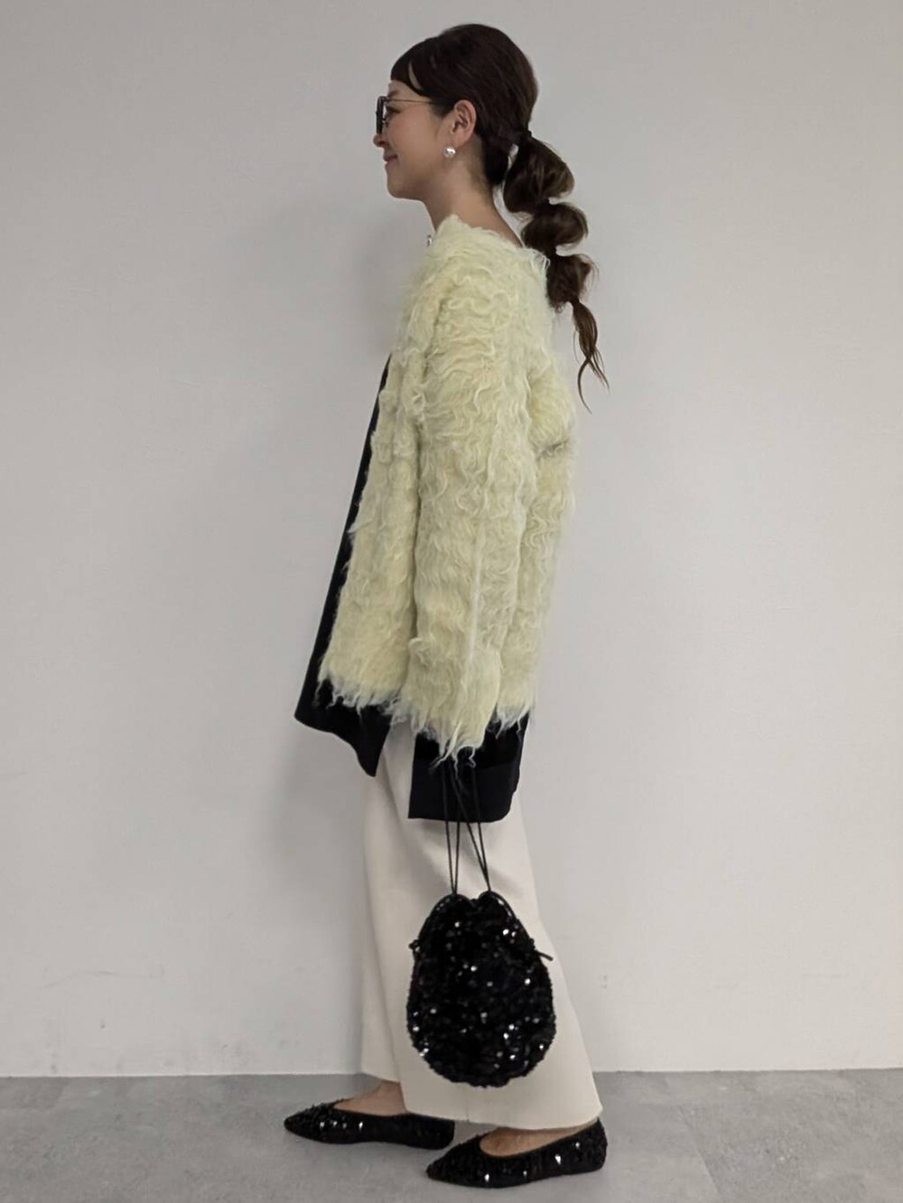 ブラック系のパンプス、ブラック系のショルダーバッグ、ホワイト系のスカートを着用したレディースの秋コーディネートの2枚目の写真