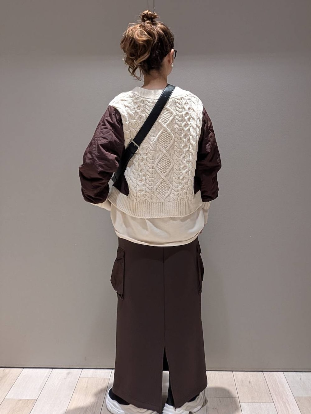 ブラック系のショルダーバッグ、ブラウン系のスカート、ホワイト系のカーディガン/ボレロを着用したレディースの秋コーディネートの4枚目の写真
