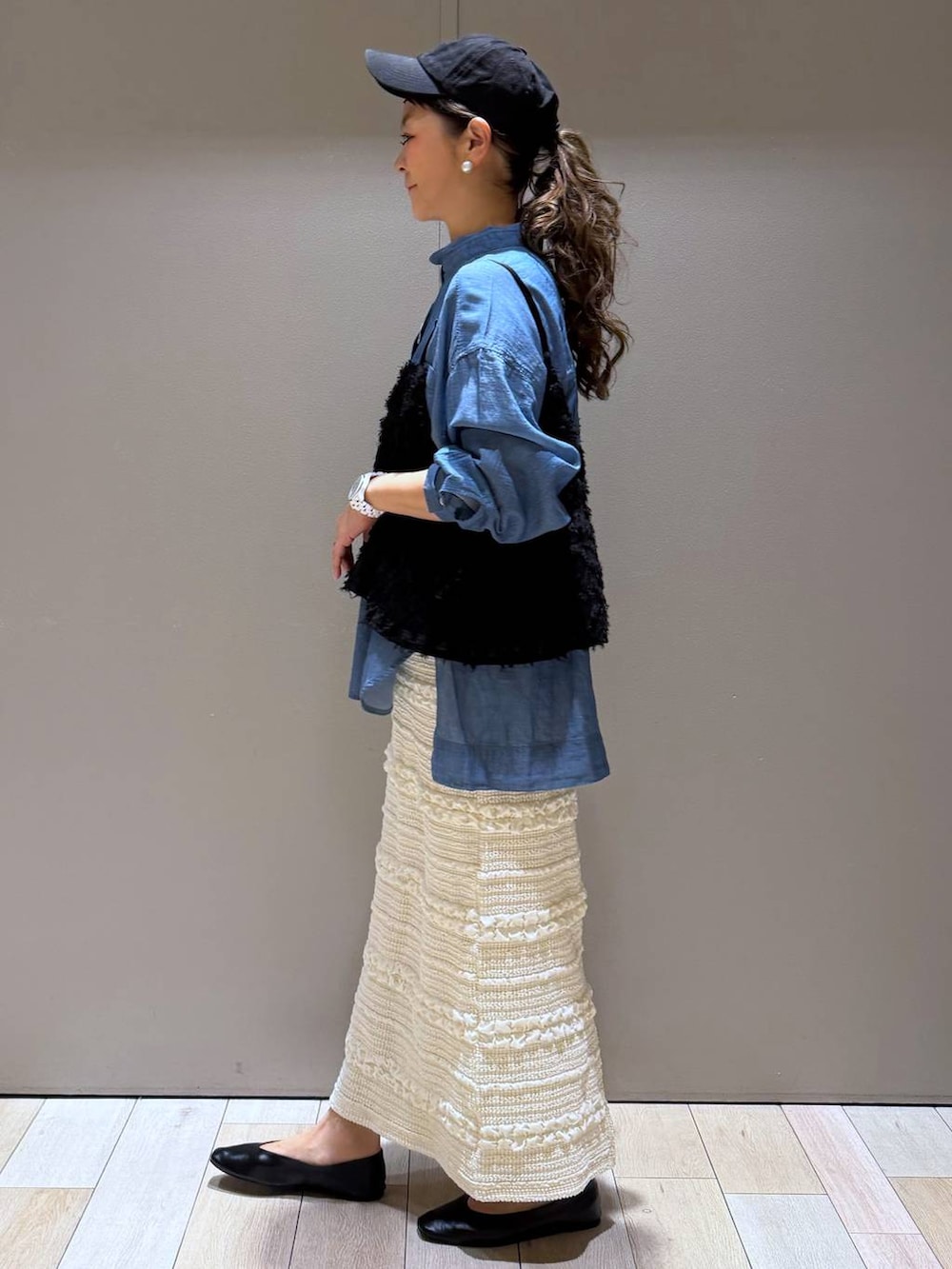 ブラック系のショルダーバッグ、ブラック系のパンプス、ブルー系のシャツ/ブラウスを着用したレディースの春コーディネートの2枚目の写真