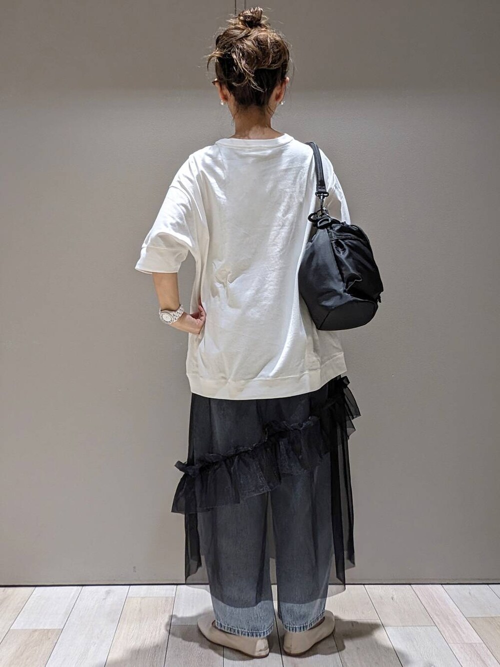 ブラック系のスカート、ホワイト系のパンプス、ブラック系のショルダーバッグを着用したレディースの春コーディネートの3枚目の写真