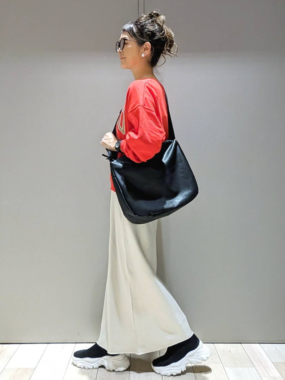 レッド系のスウェット、ブラック系のショルダーバッグ、ホワイト系のスカートを着用したレディースの冬コーディネートの2枚目の写真