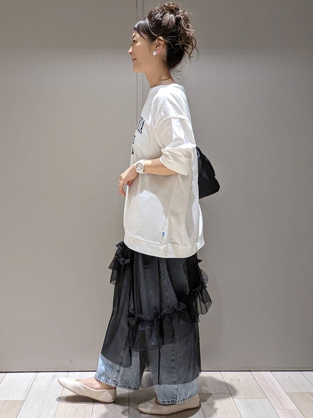 ブラック系のスカート、ホワイト系のパンプス、ブラック系のショルダーバッグを着用したレディースの春コーディネートの2枚目の写真
