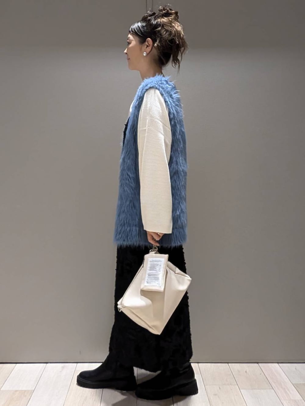 ブラック系のブーツ、ホワイト系のニット/セーター、ブラック系のドレスを着用したレディースの秋コーディネートの2枚目の写真