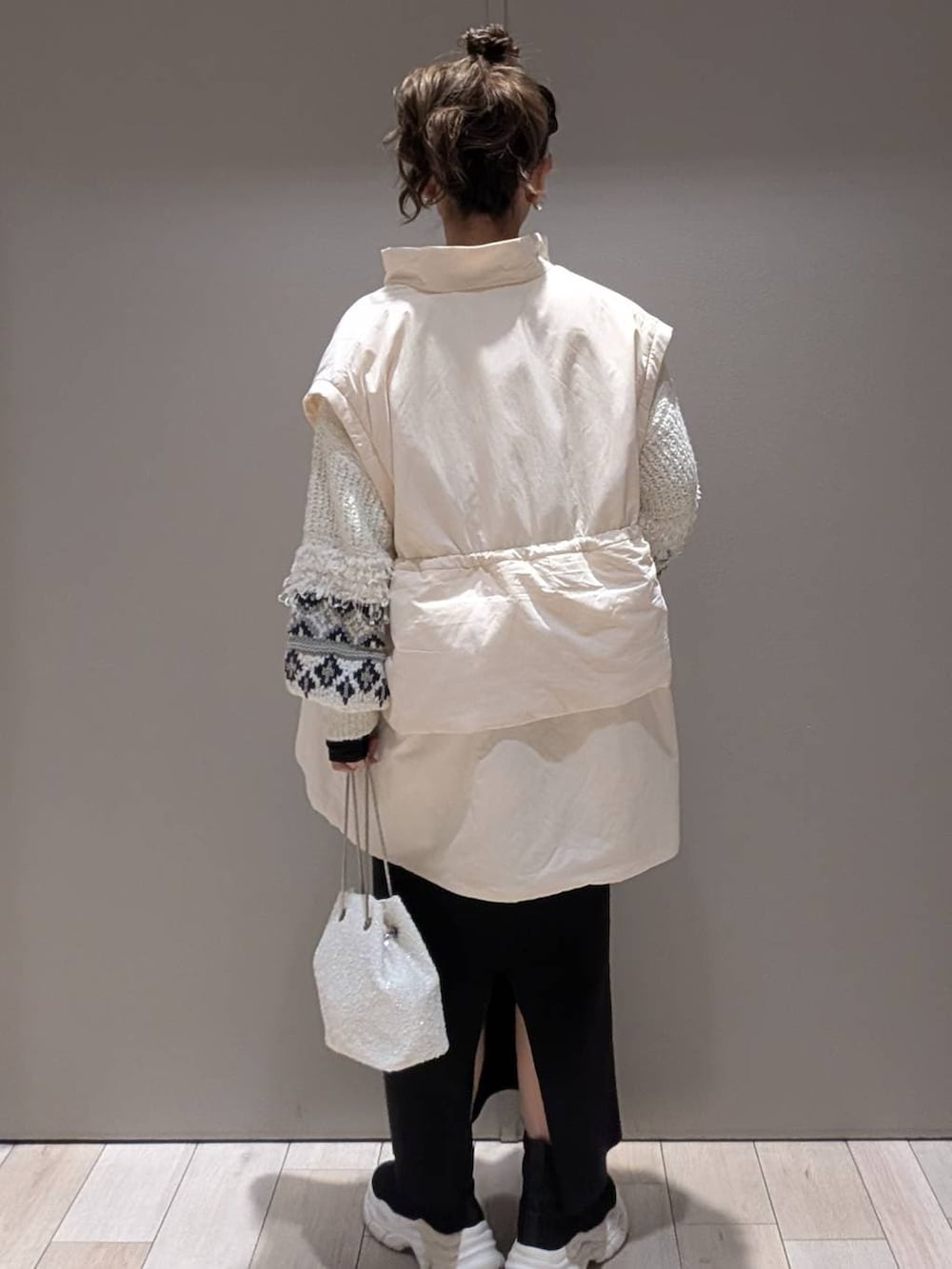 ブラック系のスカート、ブラック系のブーツ、ホワイト系のショルダーバッグを着用したレディースの秋コーディネートの3枚目の写真