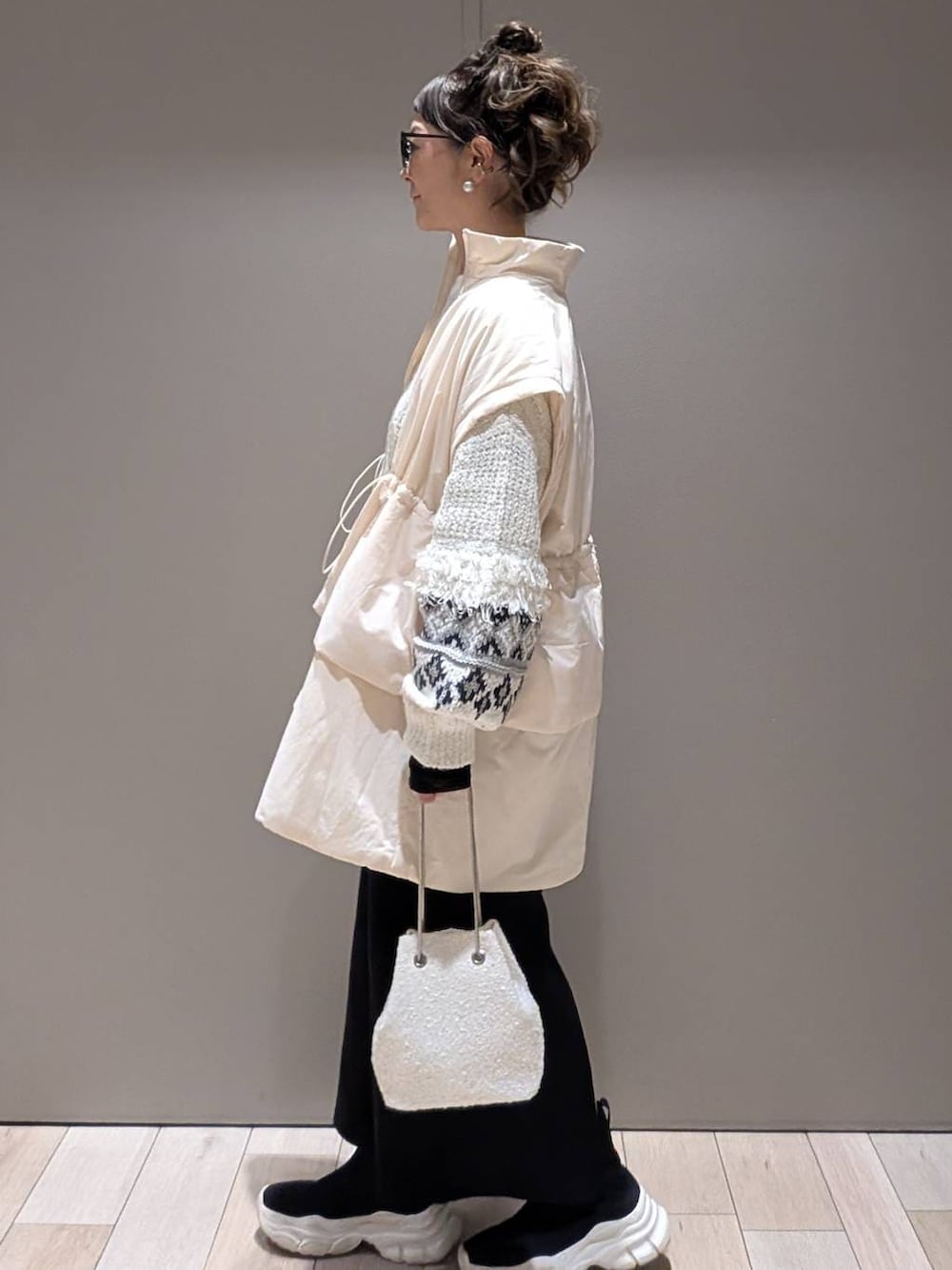 ブラック系のスカート、ブラック系のブーツ、ホワイト系のショルダーバッグを着用したレディースの秋コーディネートの2枚目の写真