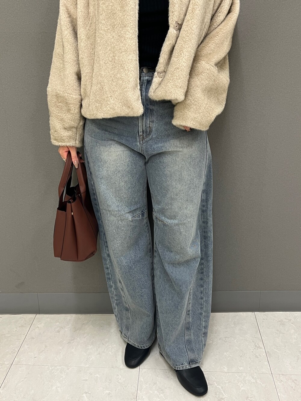ベージュ系のブルゾン、ブラック系のニット/セーター、ブルー系のデニムパンツを着用したレディースの秋コーディネートの3枚目の写真