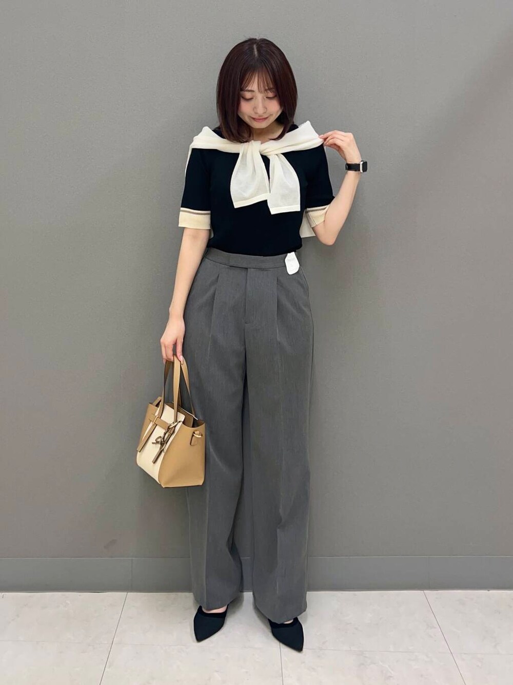 ブラック系のパンプス、グレー系のその他パンツ、ベージュ系のトートバッグを着用したレディースの春コーディネートの2枚目の写真