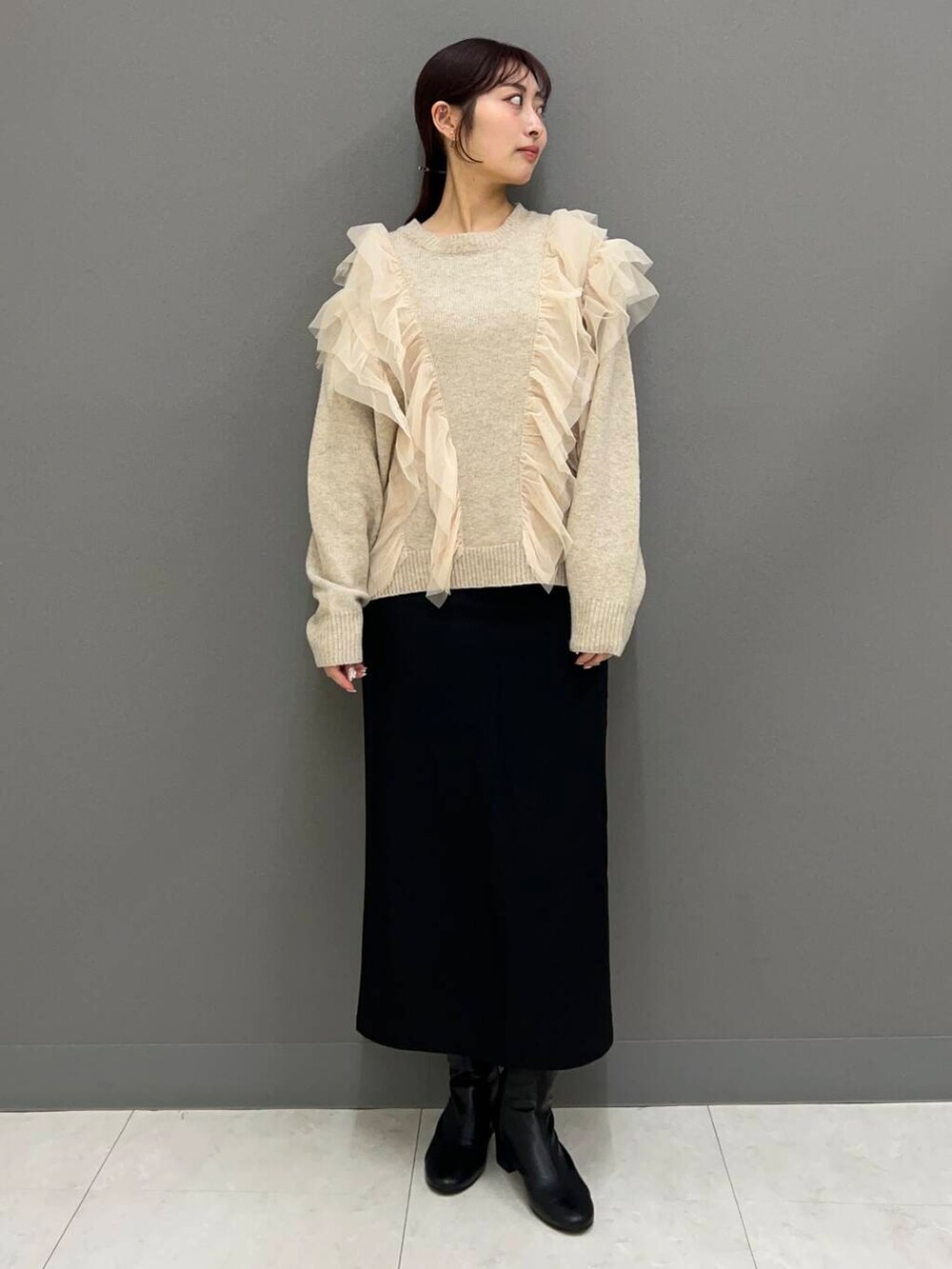 ブラック系のブーツ、ベージュ系のその他アウター、レッド系のショルダーバッグを着用したレディースの冬コーディネートの2枚目の写真