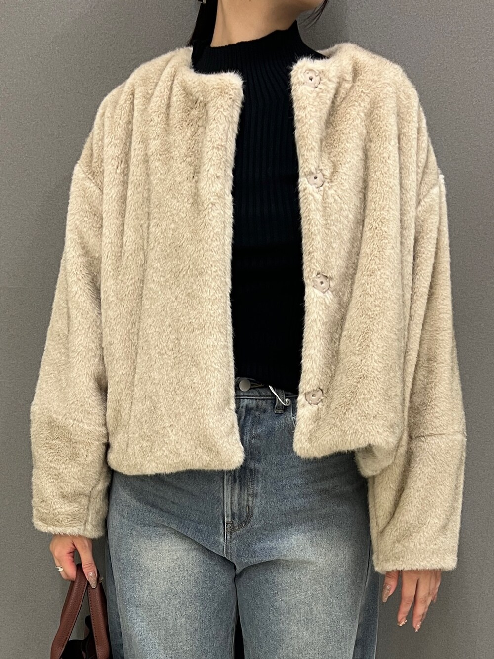 ベージュ系のブルゾン、ブラック系のニット/セーター、ブルー系のデニムパンツを着用したレディースの秋コーディネートの2枚目の写真