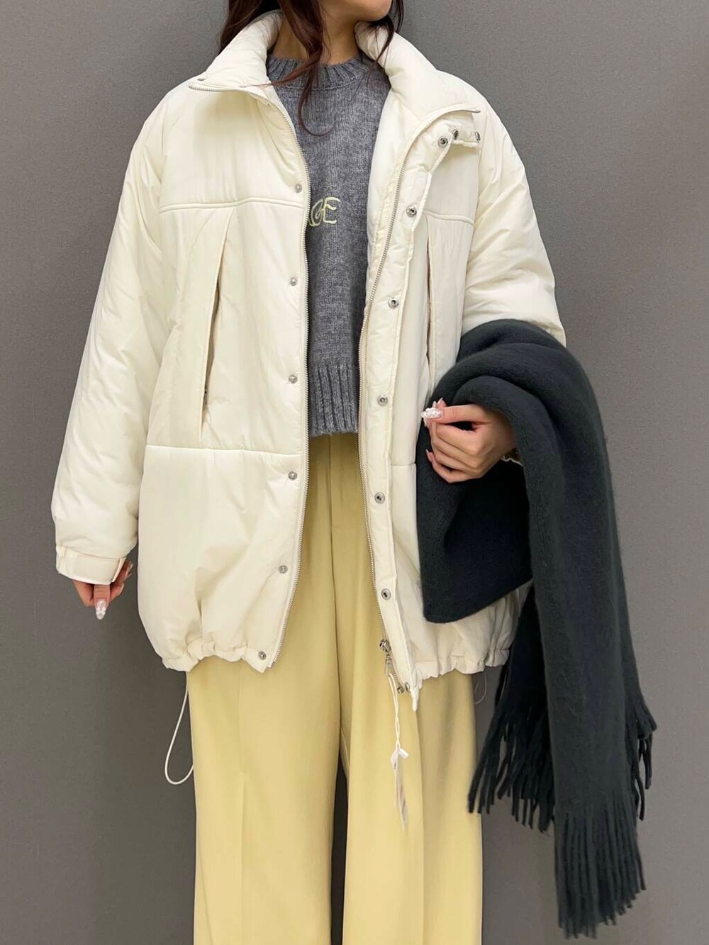 グレー系のニット/セーター、ブラック系のローファー、ホワイト系のダウンジャケット/コートを着用したレディースの冬コーディネートの3枚目の写真