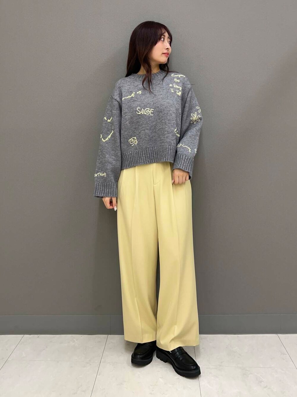 グレー系のニット/セーター、ブラック系のローファー、ホワイト系のダウンジャケット/コートを着用したレディースの冬コーディネートの2枚目の写真