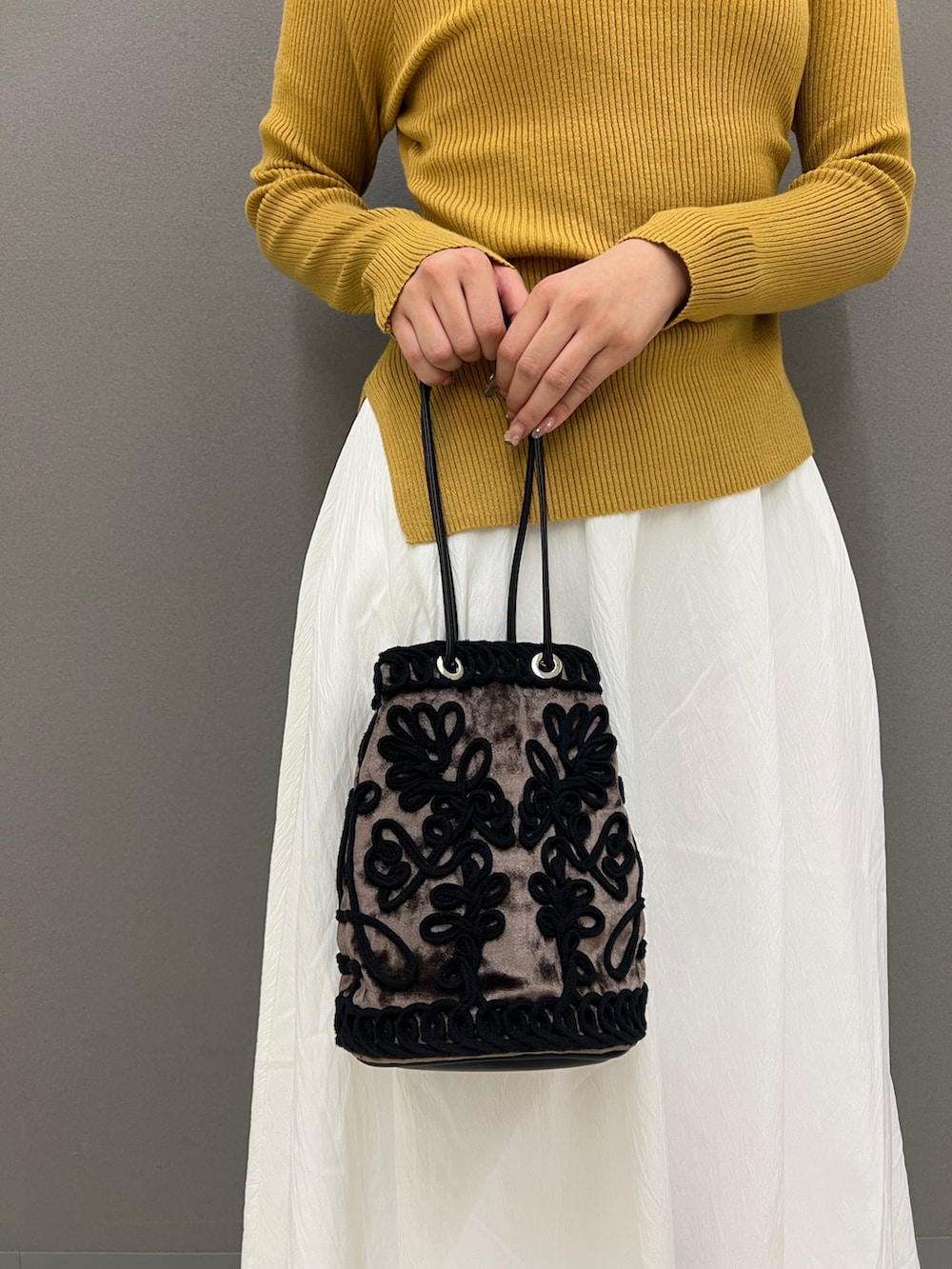 イエロー系のニット/セーター、ホワイト系のスカート、ブラック系のその他シューズを着用したレディースの秋コーディネートの5枚目の写真