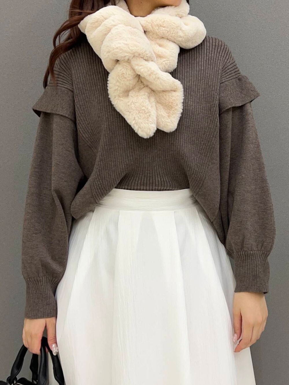 ブラック系のブーツ、ブラック系のハンドバッグ、ブラウン系のニット/セーターを着用したレディースの冬コーディネートの3枚目の写真